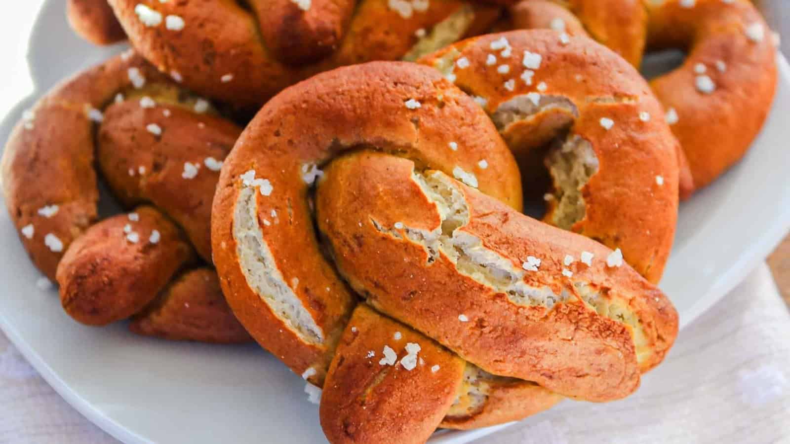 Golden brown soft pretzels topped with coarse salt on a white plate.
