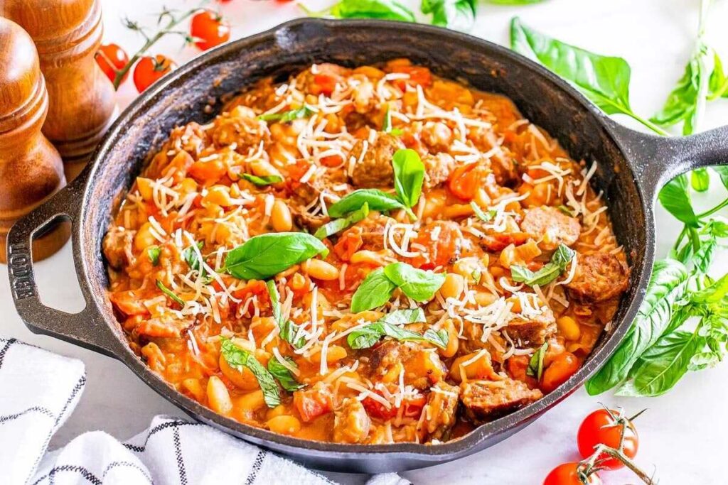 Italian cannellini bean and sausage skillet dinner topped with grated cheese and basil leaves.