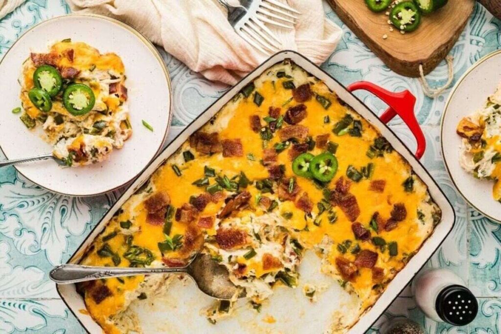 Cheesy jalapeño popper casserole topped with sliced jalapeños and green onions.