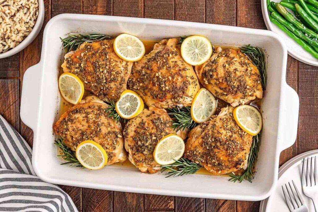 Lemon rosemary chicken thighs baked with lemon slices, served with green beans and rice.