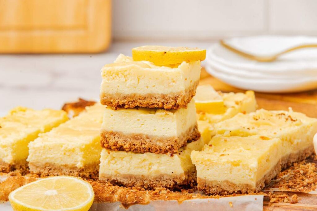 A stack of lemon cheesecake bars topped with fresh lemon slices.