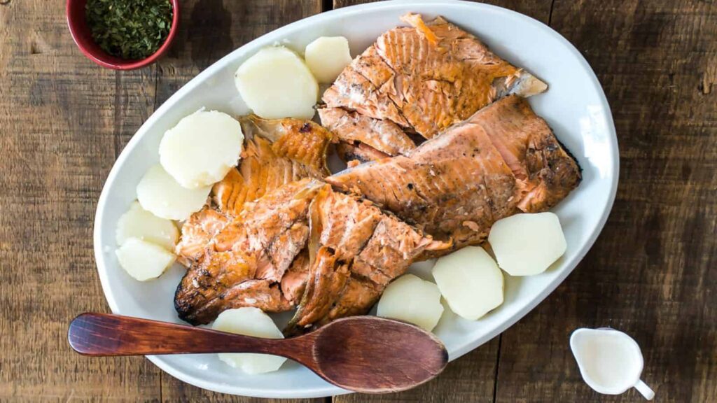 Overhead view of fire-grilled salmon in white plate.