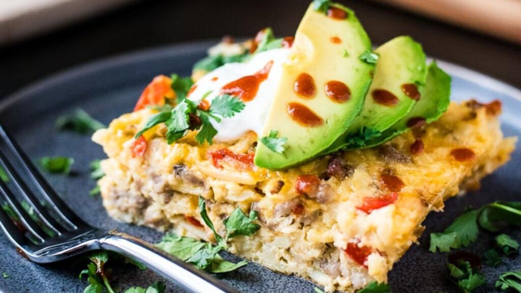 An overhead shot of breakfast casserole next to a single serving and a toppings bar.