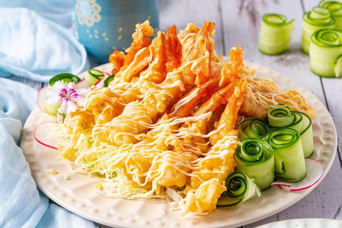 A bowl of crispy fried shrimp with slices of green onions and jalapeños.