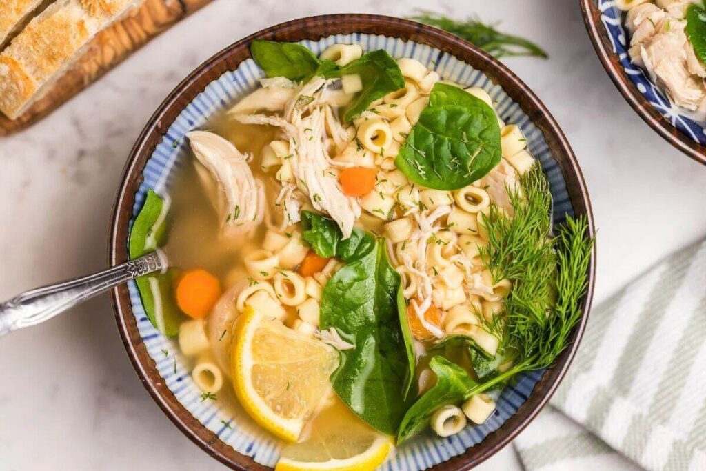 A bowl full of chunky chicken and noodle soup.