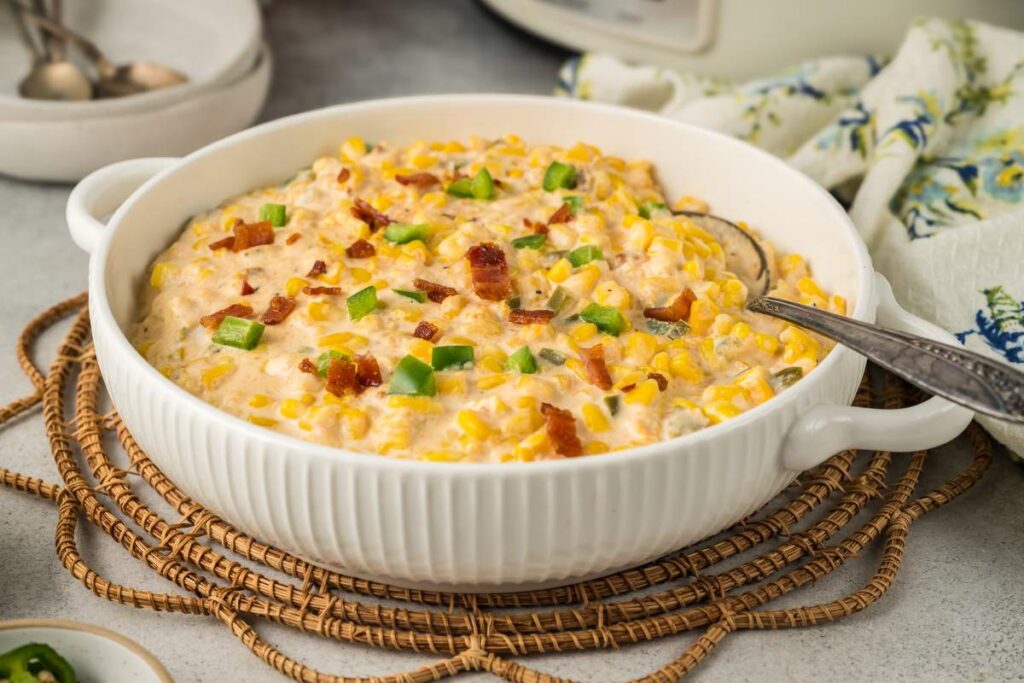 Slow cooker jalapeño corn dip topped with bacon and chopped peppers.