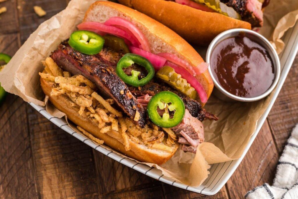 Enjoy the best BBQ brisket sandwich topped with fried onions, jalapeños, pickles, and pickled onions, served with savory barbecue sauce. 