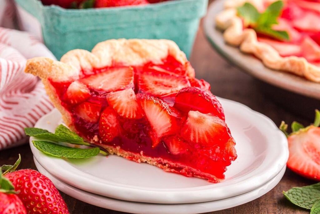 A slice of fresh strawberry pie on a white plate.