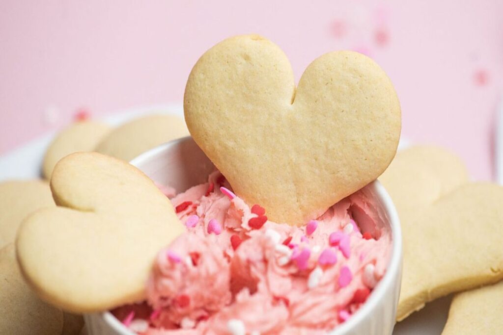 Heart shaped Valentine’s day sugar cookies in pink frosting with sprinkles.