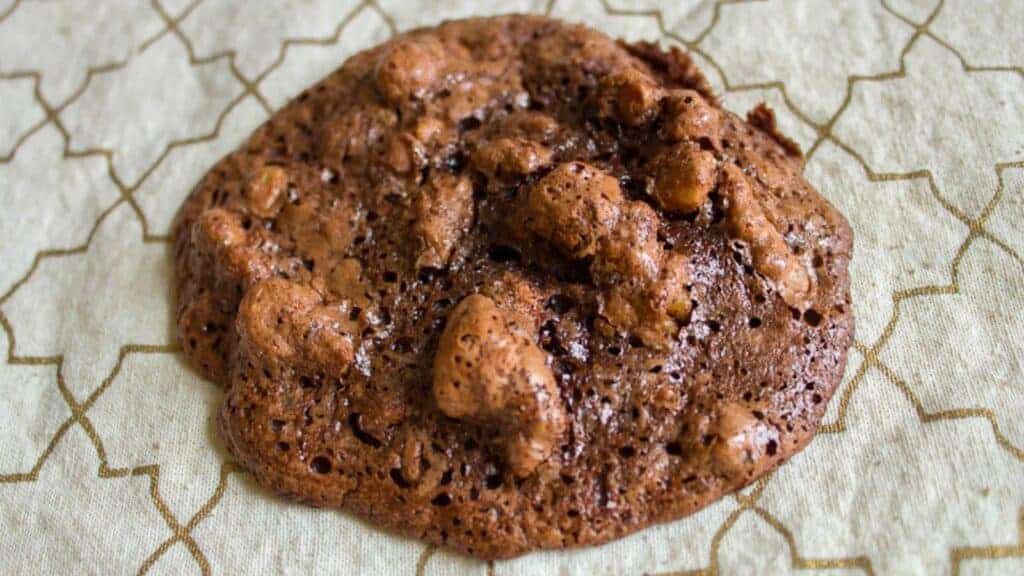 Chocolate cookies with visible walnut pieces arranged on a flat surface.
