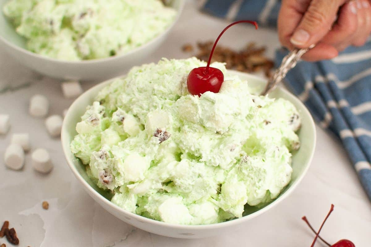 A bowl of Watergate salad topped with a cherry.