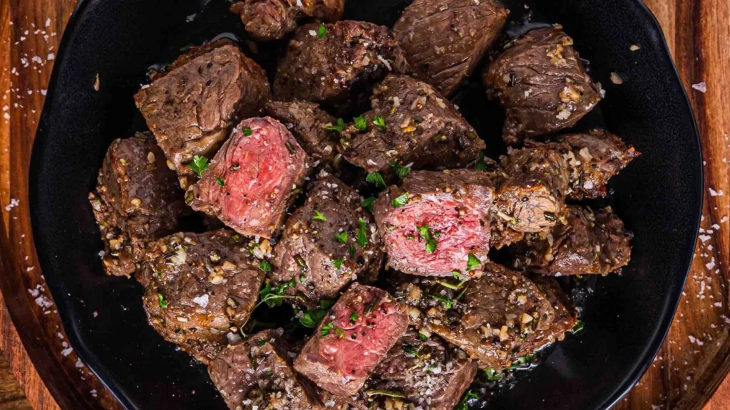 Air fryer steak bites coated in garlic butter served hot with crispy browned edges.