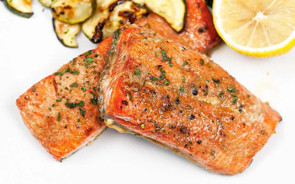 Honey garlic salmon fillets glazed and served on a white plate with garnish.