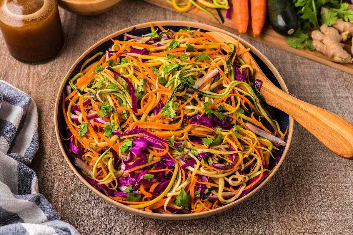 Spiralized zucchini noodles mixed with shredded vegetables in a bowl.