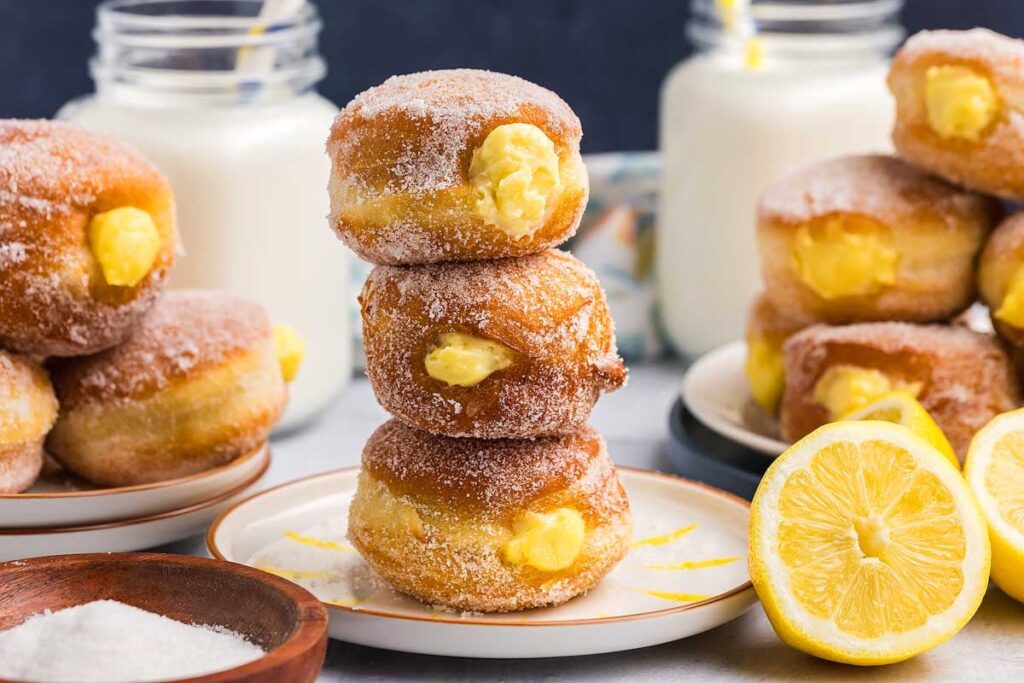 A stack of three sugar-coated bomboloni filled with lemon custard.