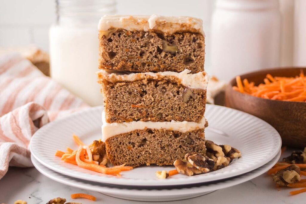 Delicious carrot cake bars with frosting, walnuts, and shredded carrots.