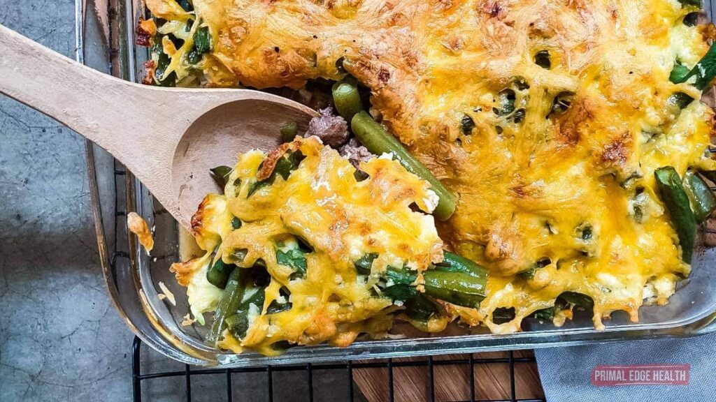 A wooden spoon scooping a serving of green bean hamburger casserole.