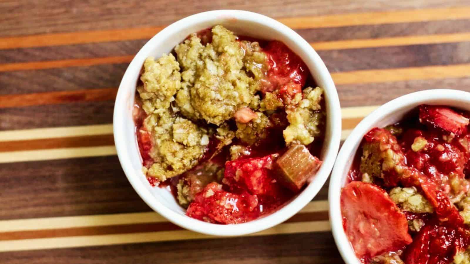 Two white ramekins filled with strawberry rhubarb crisp.