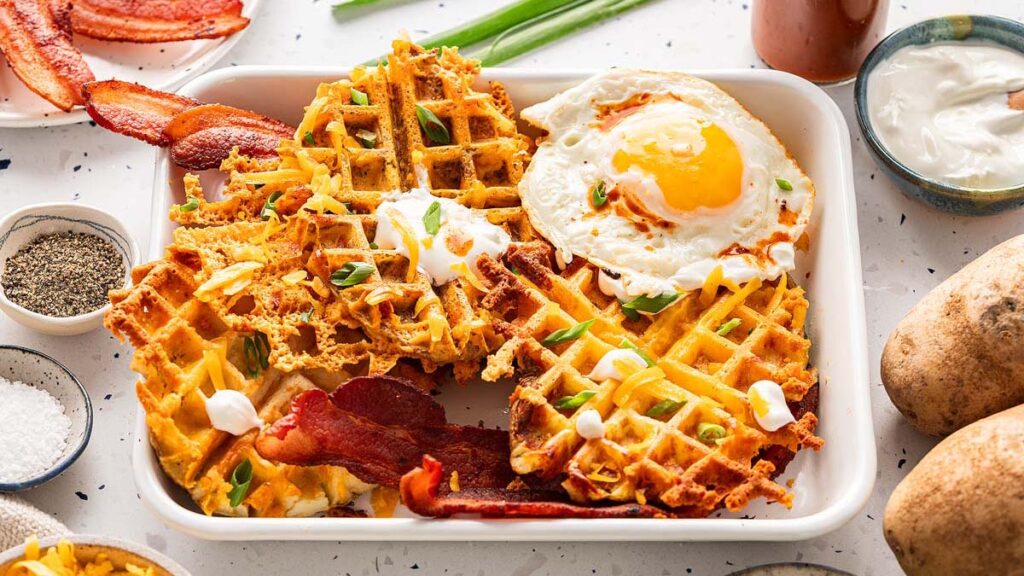 A tray full of waffles, bacons and sunny side up egg.
