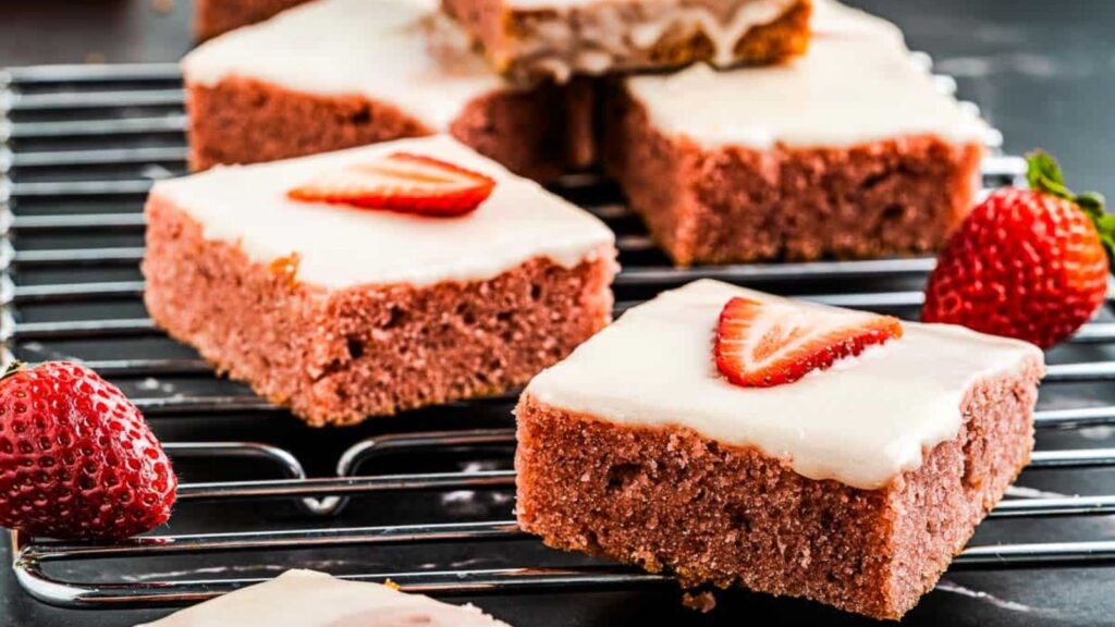 Strawberry brownies topped with pink glaze and fresh strawberry pieces.