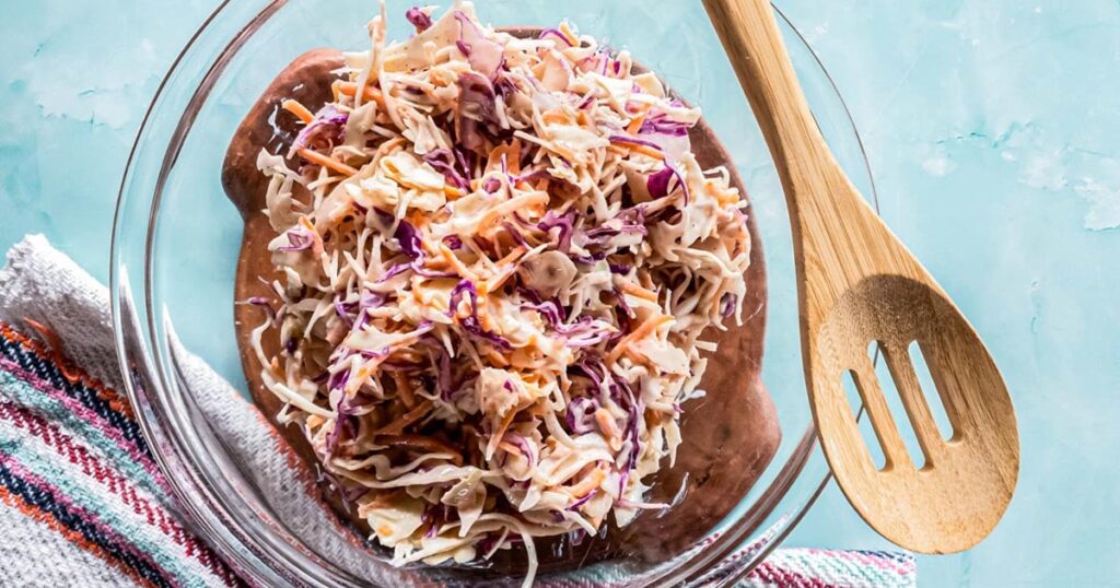 A picture of coleslaw recipe with creamy dressing in glass bowl.