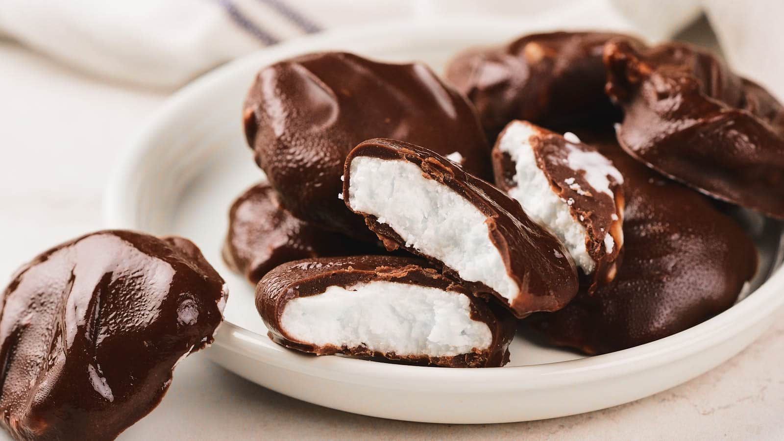 A plate of pepeprmint patties, some whole and some split open to show the inside.