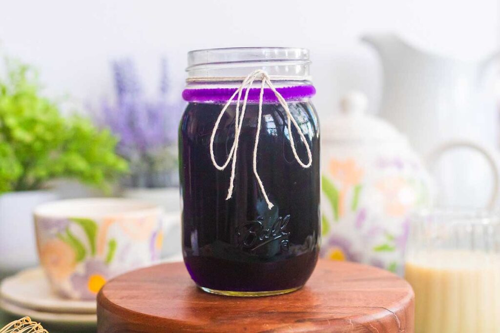 A mason jar filled with deep purple lavender simple syrup.