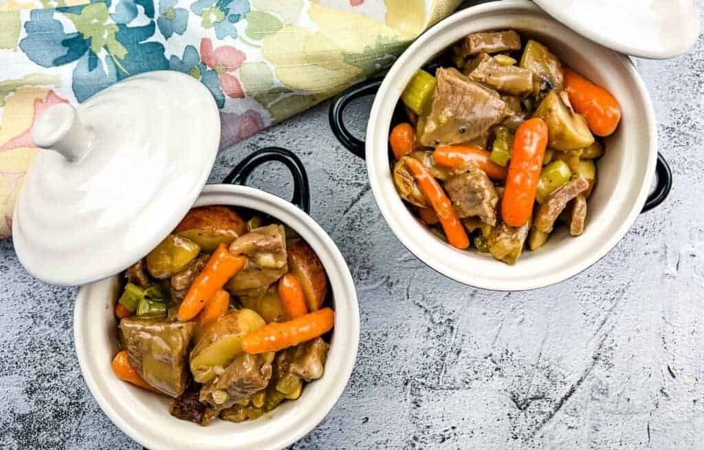 Two bowls of leftover roast beef stew on a table.
