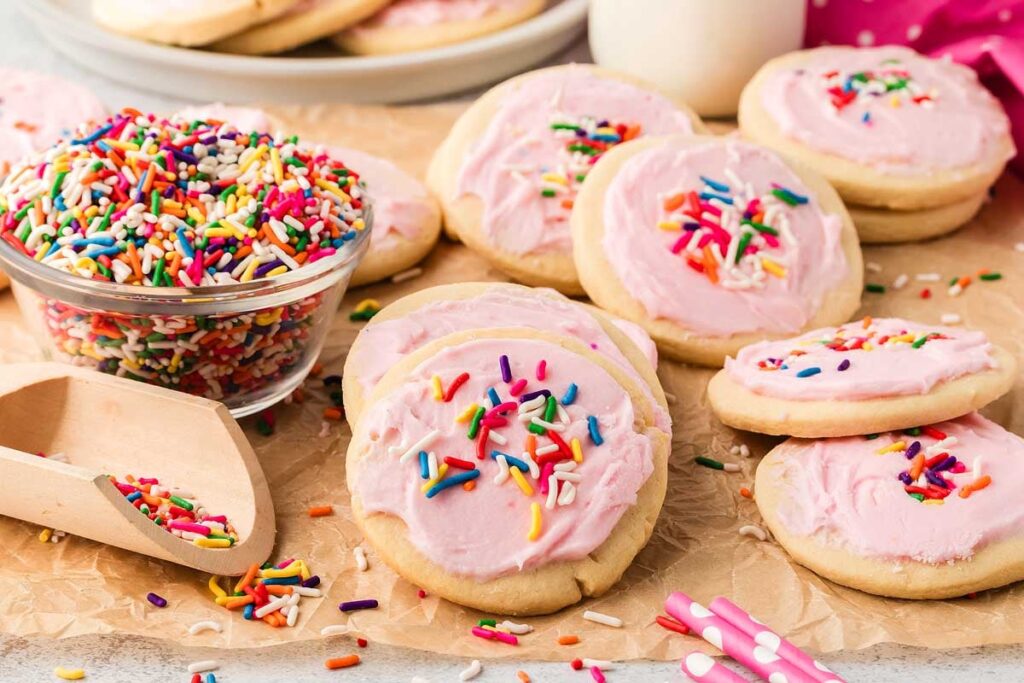 Pink frosted copycat Lofthouse cookies with sprinkles on parchment paper.