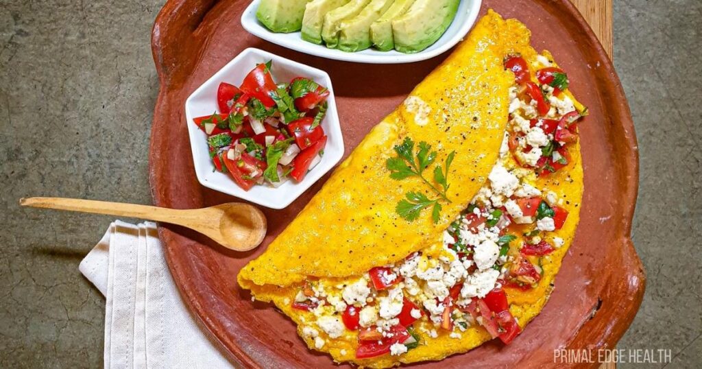 A colorful plate featuring a large omelette filled with tomatoes and cheese.