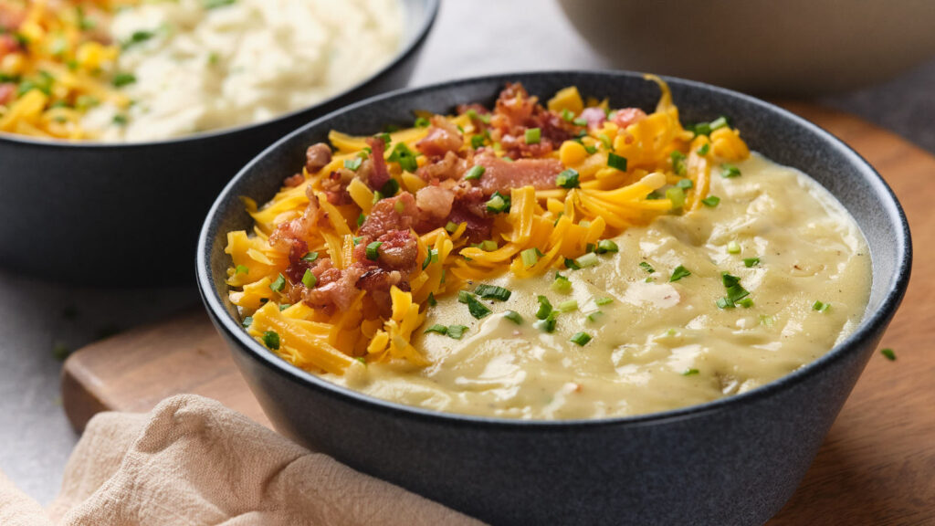 A close-up of two bowls filled with creamy potato soup.
