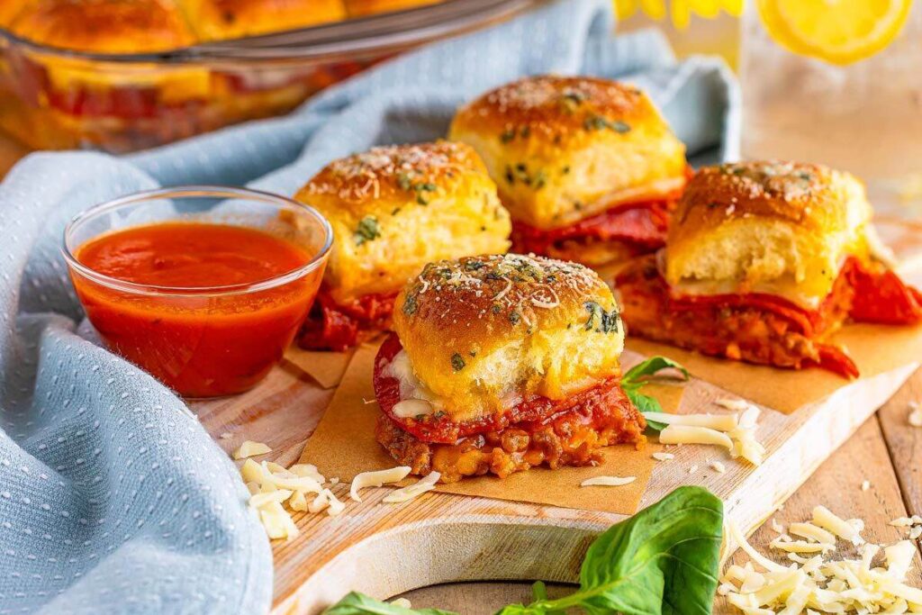 Freshly baked easy pepperoni pizza sliders with a side of marinara sauce.
