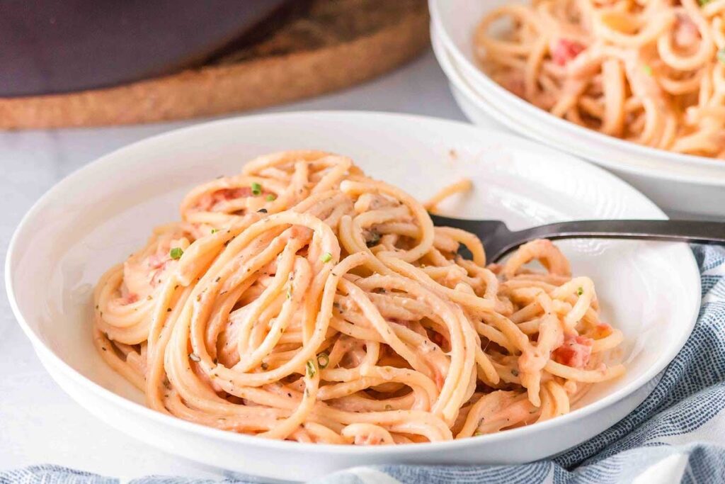 A bowl of spaghetti with a fork and pink pasta sauce.