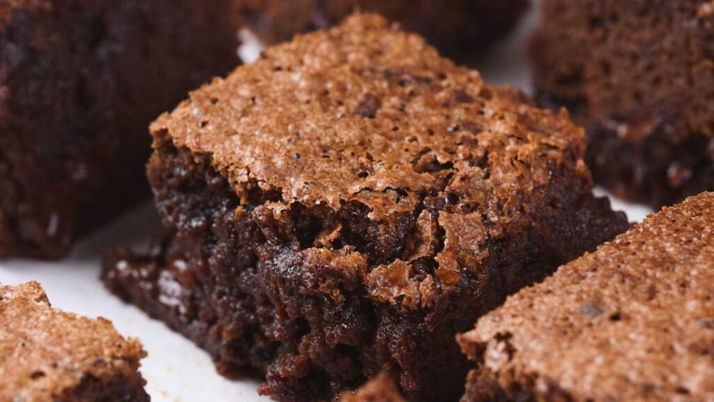A close up shot of a pumpkin brownie on a white surface.