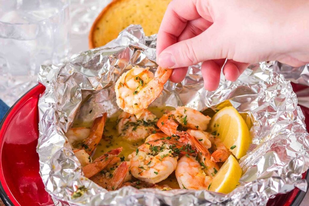 A hand holding a piece of shrimp foil packet.