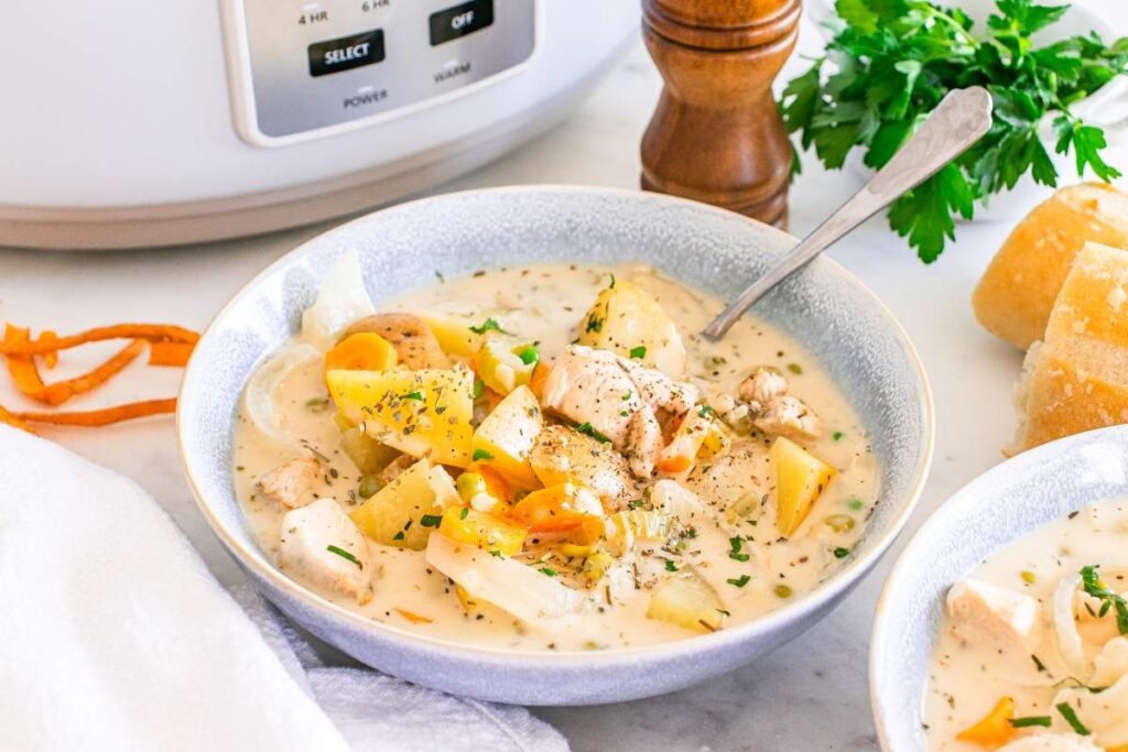 A creamy slow cooker chicken stew with vegetables in a bowl, garnished with herbs. 