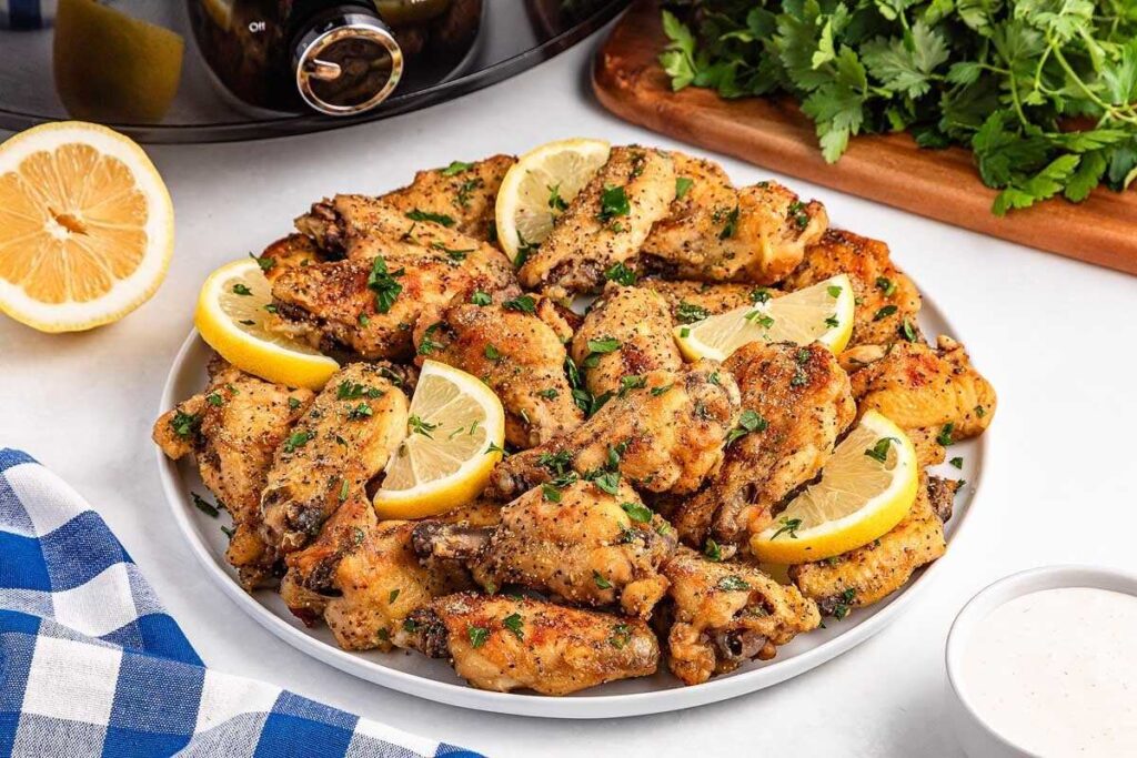 Slow cooker lemon pepper wings garnished with lemon and parsley.