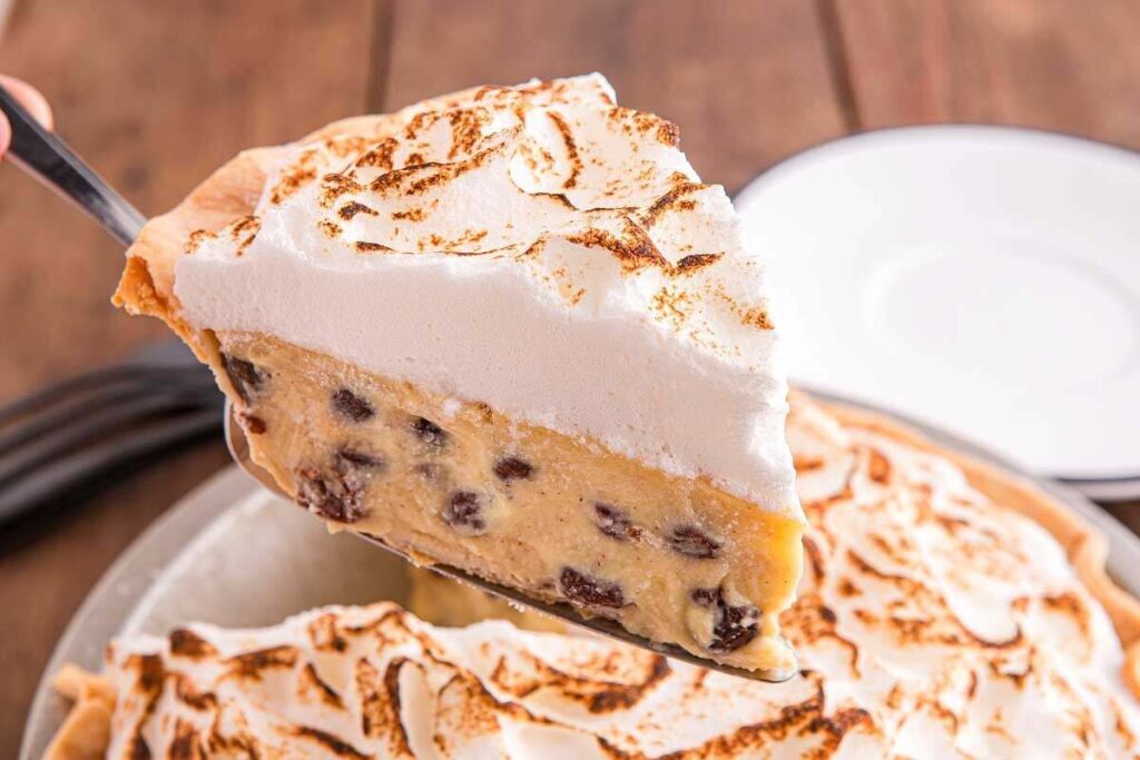 A slice of meringue-topped sour cream raisin pie is lifted from the metal pan.