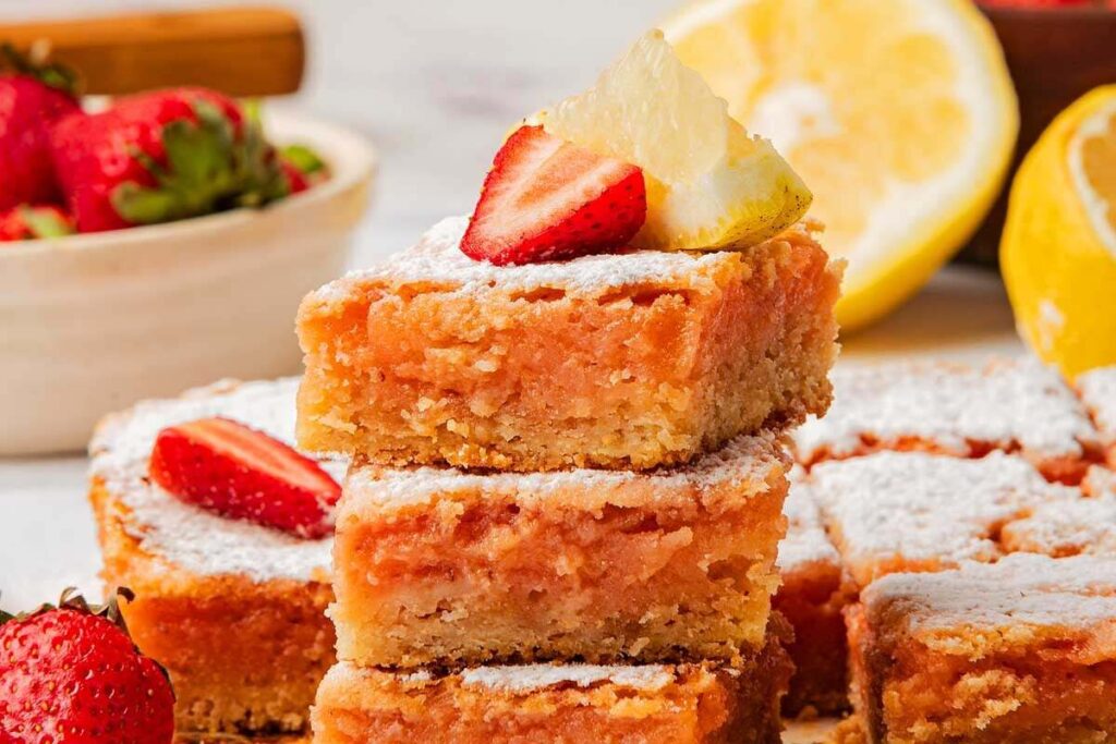 Strawberry lemonade bars topped with fresh strawberries and lemon slices.