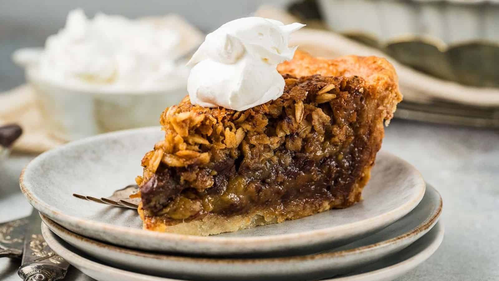 Slice of Black Bottom Oatmeal Pie topped with whipped cream on a stack of plates with a fork beside it.