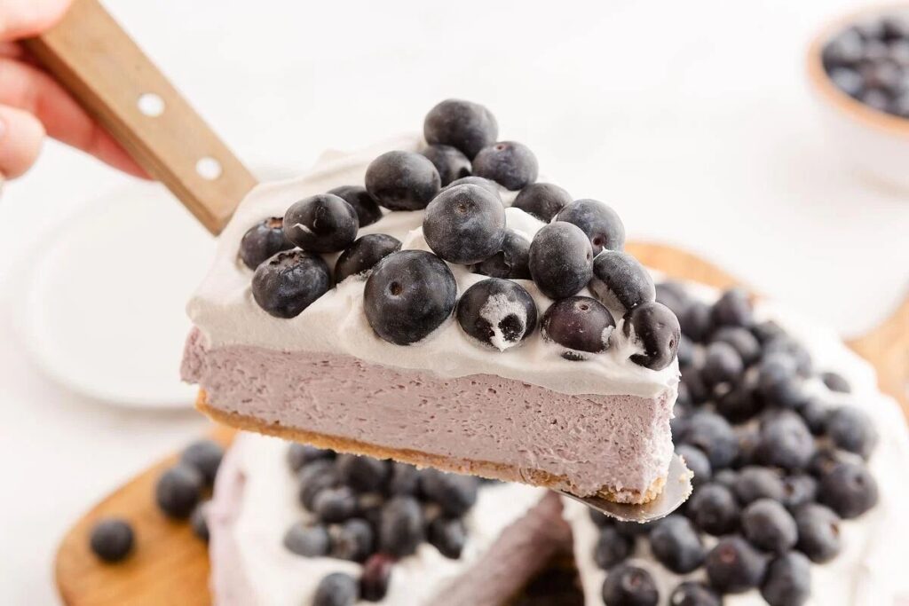  A slice of no bake blueberry cheesecake with whipped cream and fresh blueberries on top.