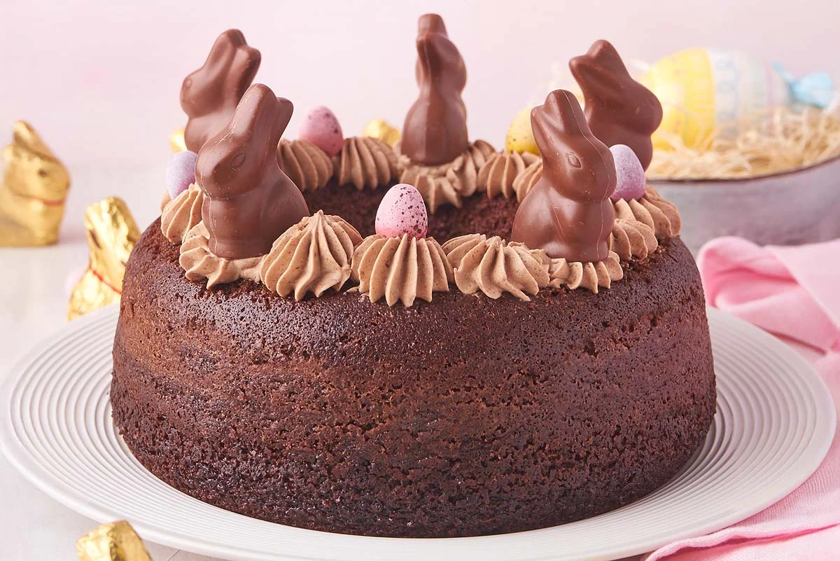 Chocolate bundt cake with glaze topped with small decorative candies on a plate.