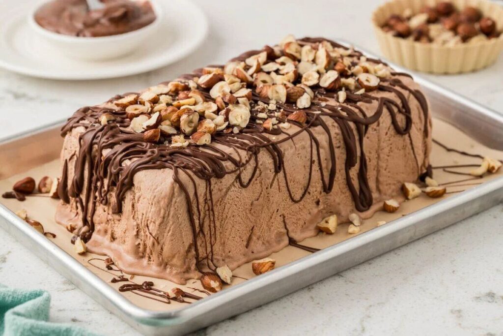 Chocolate Hazelnut Semifreddo cake topped with chopped hazelnuts and chocolate drizzle on a baking tray.