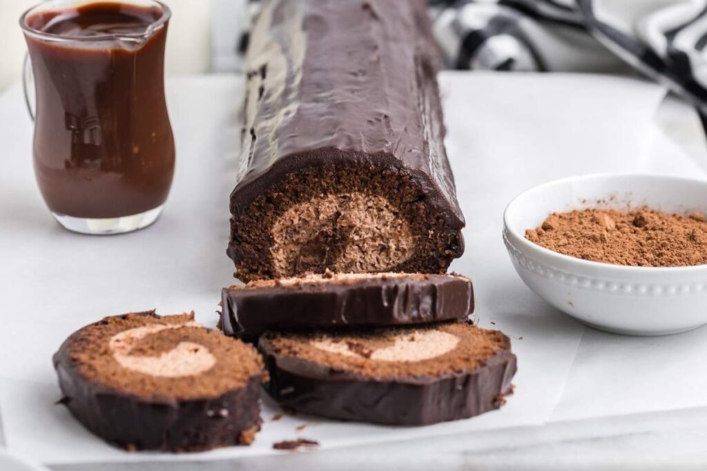 A delectable chocolate roll cake, sliced on a table, unveils its cream filling.