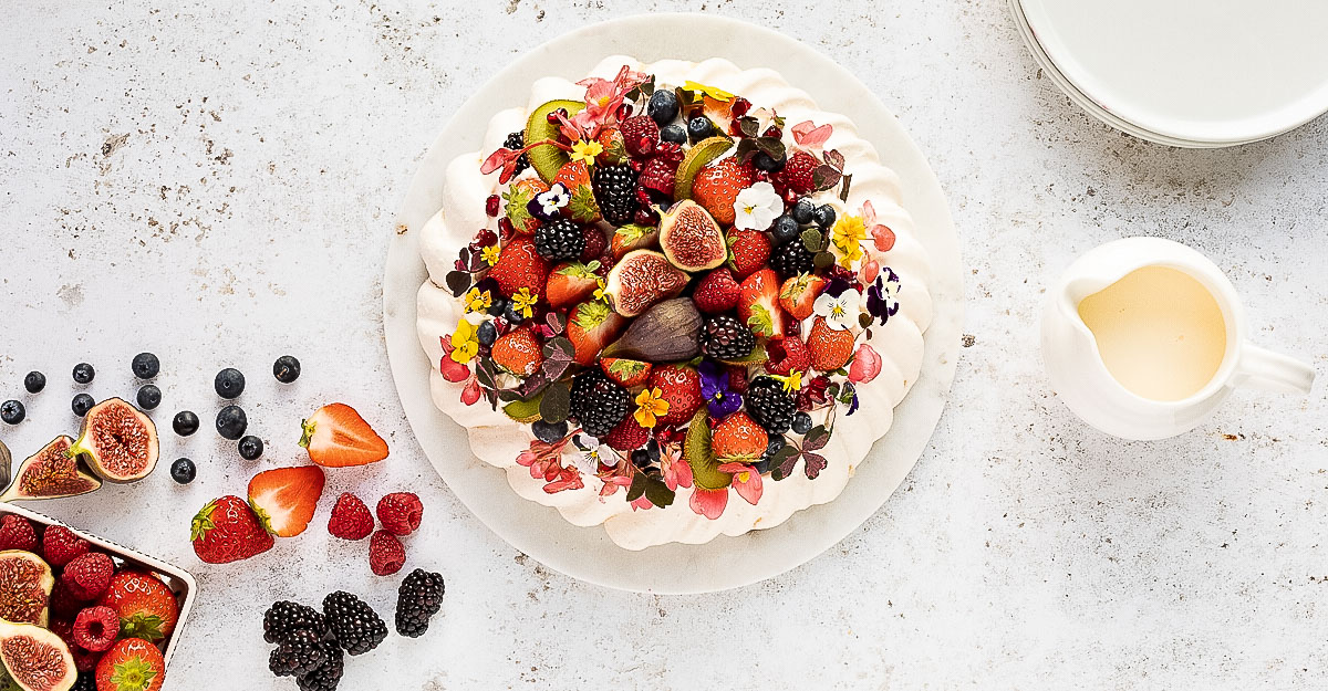 A pavlova topped with berries and figs.
