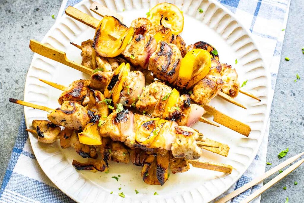 Grilled Greek lemon chicken kabobs with herbs and lemon slices.