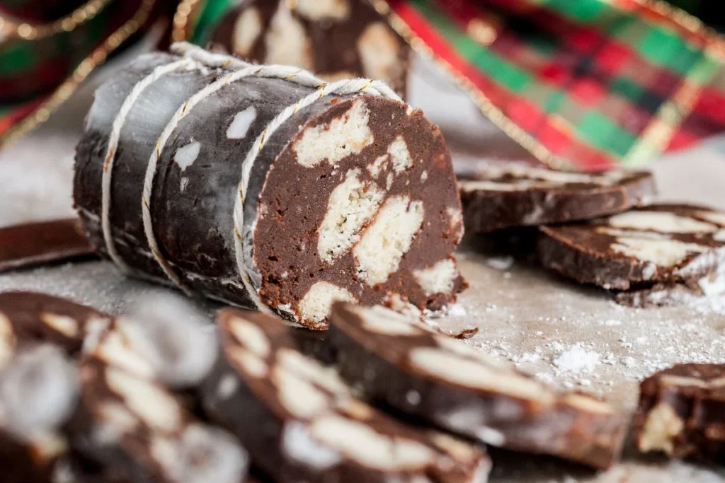 Sliced Italian Chocolate Salami – Salame di Cioccolato with biscuit pieces sits on a surface, showcasing this no bake treat.
