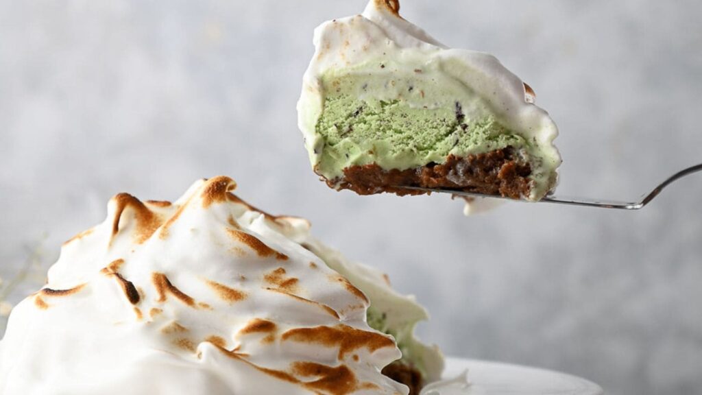 A slice of baked Alaska on a cake slice above the pie with a slice removed.