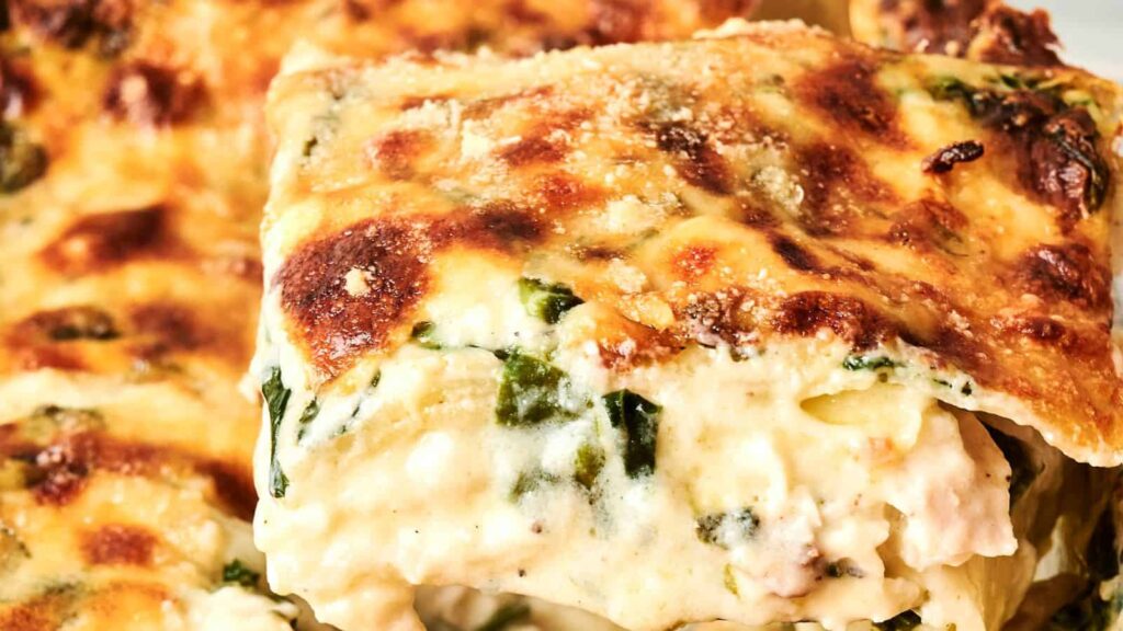 Close-up of a slice of creamy vegetable lasagna with a golden-brown cheese crust.