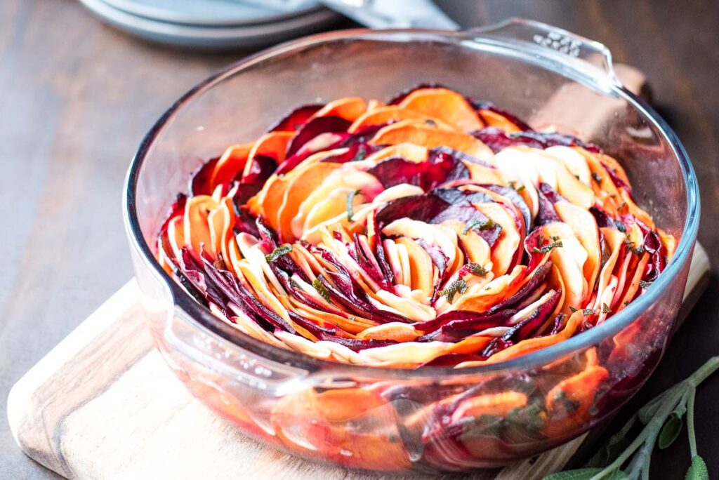 Oven Roasted Root Vegetables in a glass dish on a wooden board.